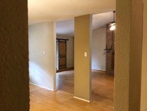 Temple house for rent - A room with a wooden floor and a white wall with a doorway leading to another room.