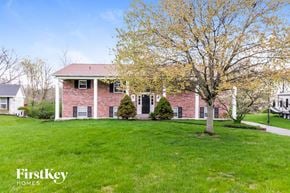 West Chester house for rent - a red brick house with a green lawn and a tree