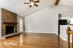 Ballwin house for rent - an empty living room with a brick fireplace and a ceiling fan