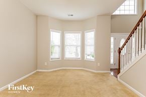 Hampton house for rent - A spacious room with a carpeted floor and a staircase on the right side.