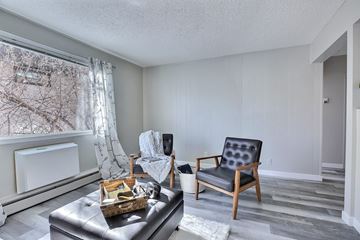 Regina apartment for rent - A living room with a black leather chair and a white sofa.