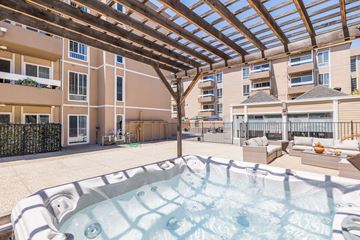 Oakland apartment for rent - A hot tub is in the middle of a patio with a wooden pergola above it.