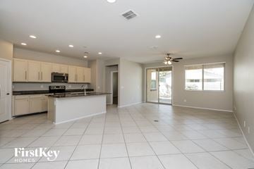 Tolleson house for rent - A spacious kitchen and living room with white tile flooring and a ceiling fan.