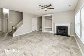 Charlotte house for rent - an empty living room with a fireplace and a staircase
