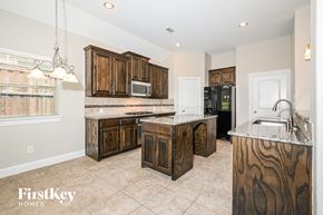 Garland house for rent - a kitchen with wooden cabinets and marble counter tops and a sink