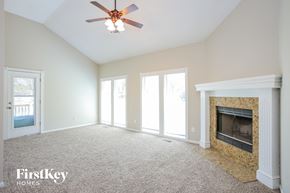 Kansas City house for rent - A spacious living room with a fireplace and a ceiling fan.