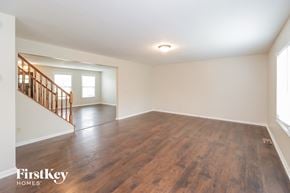 Morrow house for rent - A spacious room with wooden flooring and a staircase on the left side.