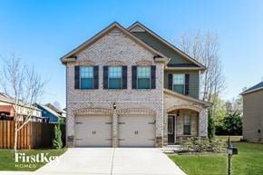 Braselton house for rent - a white brick house with two garage doors