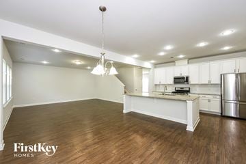 Moncks Corner house for rent - an open kitchen and living room with white cabinets and a kitchen island