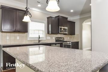 Whitsett house for rent - a kitchen with granite counter tops and dark cabinets