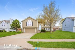Raymore house for rent - a beige house with a driveway and a lawn
