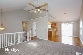 Raymore house for rent - an empty living room with a ceiling fan and a kitchen