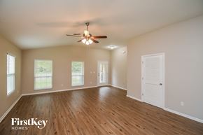 Jacksonville house for rent - A spacious room with wooden floors and a ceiling fan.
