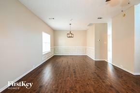 Carrollton house for rent - A large empty room with wooden floors and a chandelier hanging from the ceiling.