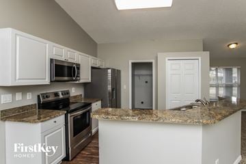 Palm Bay house for rent - a kitchen with white cabinets and a granite counter top