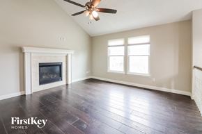 Raymore house for rent - an empty living room with a fireplace and a ceiling fan