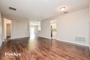 North Port house for rent - the living room and dining room of an apartment with wood flooring and white walls
