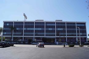 Long Beach apartment for rent - A large building with a parking lot in front.