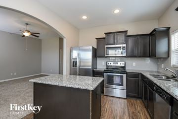 Crowley house for rent - a kitchen with black cabinets and stainless steel appliances and granite counter tops