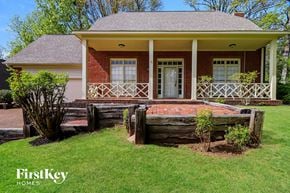 Memphis house for rent - A house with a porch and a tree stump in the front yard.