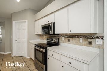 Winter Haven house for rent - a kitchen with white cabinets and a stove and a microwave