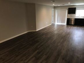 Bradenton house for rent - A room with wooden flooring and a kitchen area in the background.