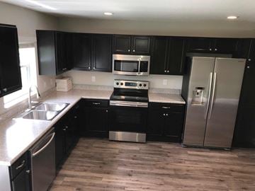 Bradenton house for rent - A kitchen with black cabinets and stainless steel appliances.