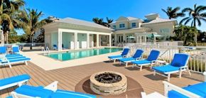 Bradenton house for rent - a large swimming pool with blue chairs and a house in the background
