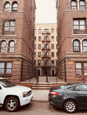 Bronx apartment for rent - two cars parked in front of two brick buildings