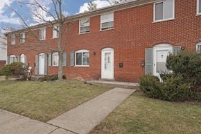 Cincinnati apartment for rent - A red brick house with a white door and a small tree in front.