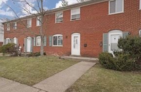 Cincinnati apartment for rent - A red brick house with a white door and a small tree in front.