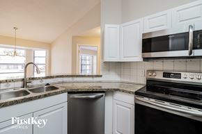 Deltona house for rent - a kitchen with white cabinets and black appliances