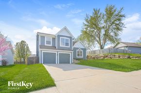 Kansas City house for rent - a blue and white house with a driveway and a lawn