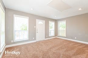 Dallas house for rent - an empty living room with three windows and a white door