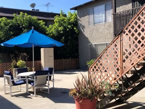 Los Alamitos apartment for rent - a patio with a blue umbrella and a table with chairs