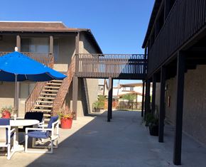 Los Alamitos apartment for rent - a patio outside a building with tables and chairs and an umbrella