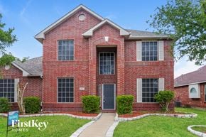 Garland house for rent - a red brick house with a black door and a lawn