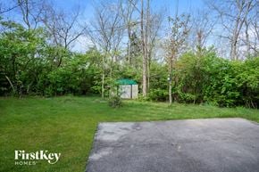 West Chester house for rent - A FirstKey Homes sign is on a grassy area with a concrete slab and trees in the background.