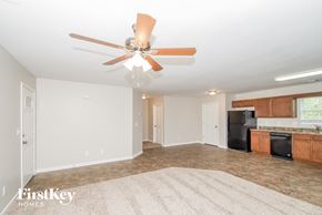 Austell house for rent - a empty living room with a ceiling fan and a kitchen