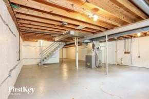 Wildwood house for rent - A spacious, empty room with a staircase and a heating unit.