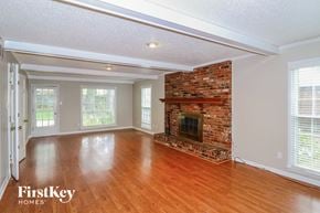 Collierville house for rent - a living room with a brick fireplace and wooden floors
