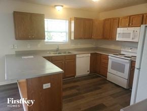 Monroe house for rent - an empty kitchen with wooden cabinets and white appliances