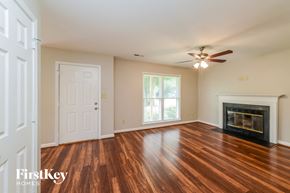 Greensboro house for rent - a living room with a fireplace and wooden floors and a ceiling fan