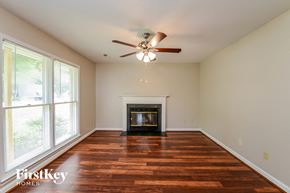 Greensboro house for rent - an empty living room with a fireplace and a ceiling fan