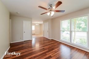 Greensboro house for rent - an empty living room with wood floors and a ceiling fan