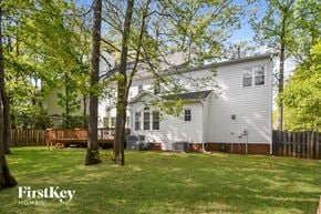 Greensboro house for rent - a white house with a backyard with trees and a wooden deck
