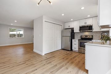 Bothell apartment for rent - an open kitchen and living room with wood floors and white cabinets