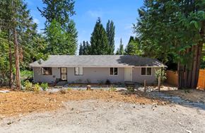 Bothell apartment for rent - a small white house with a gravel driveway and trees