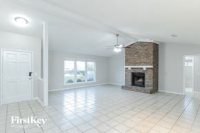 Orange Park house for rent - A spacious living room with a fireplace and a ceiling fan.