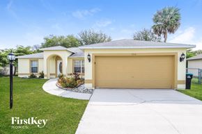 Palm Bay house for rent - a yellow house with a garage door and a driveway